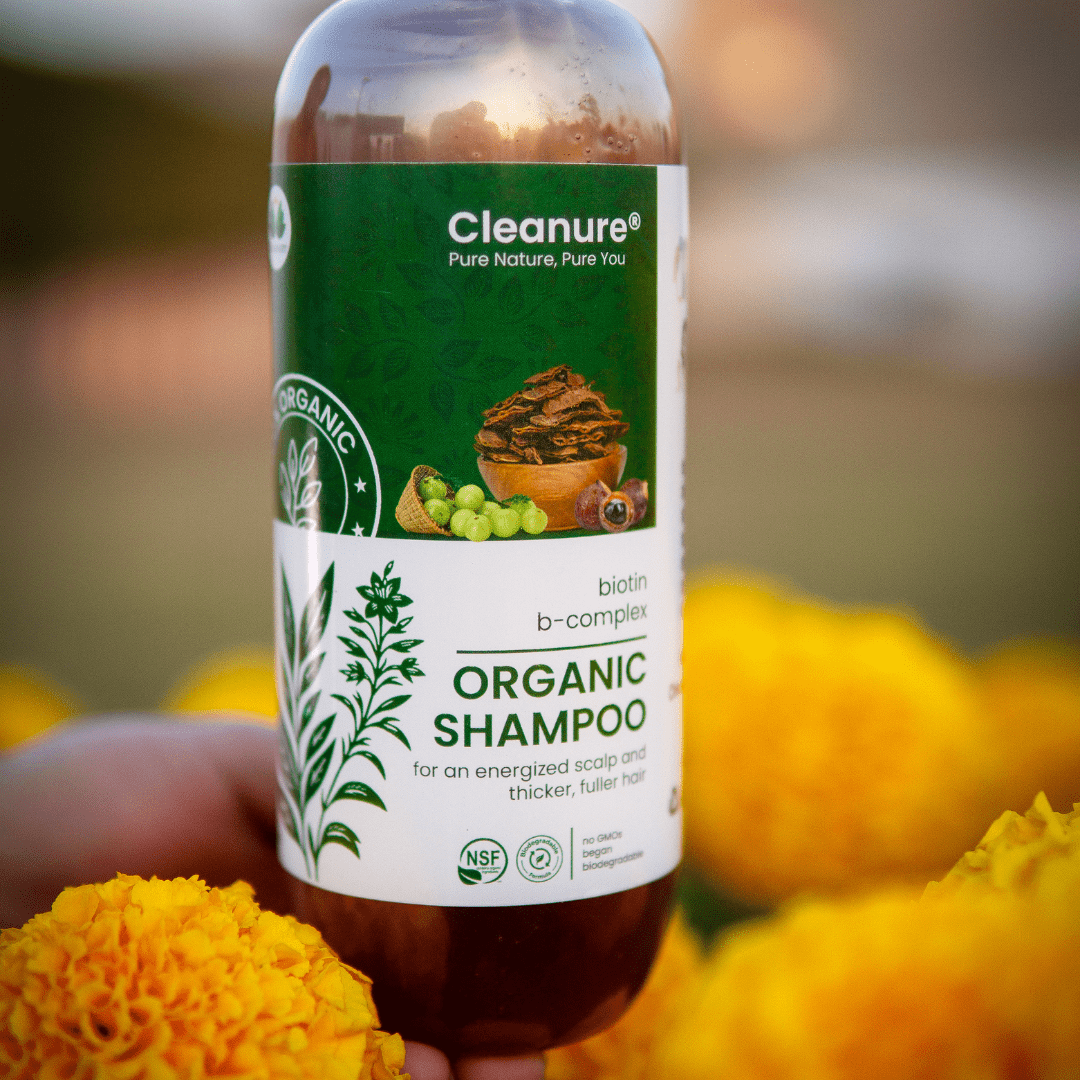 Cleanure organic shampoo bottle held in front of marigold flowers